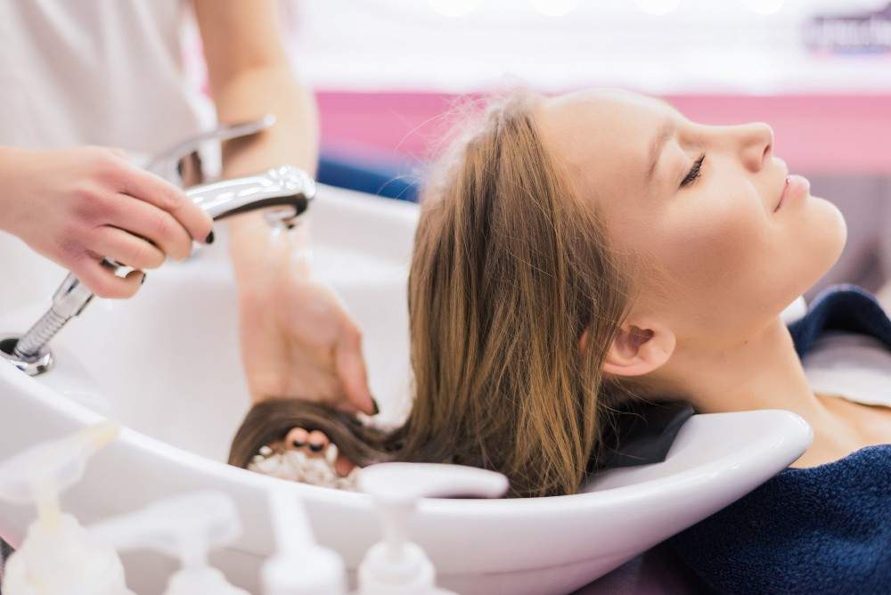 Woman enjoying a relaxing hair wash at a salon during a Premium hair treatment for ladies session.
