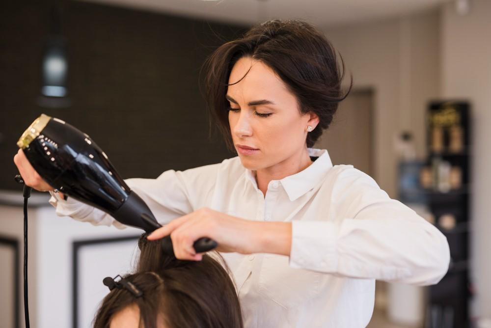 Premium hair treatment for ladies at a professional beauty salon, where a hairstylist carefully blow-dries and styles the client’s hair to give it a smooth, healthy, and shiny finish.